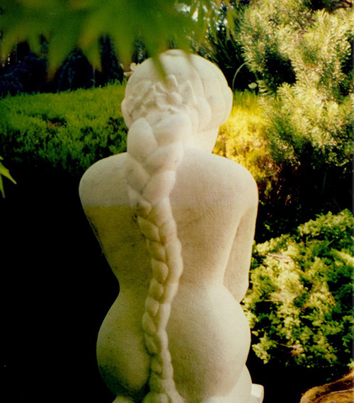 Hand carved marble sculpture of a woman, crafted in Carrara marble by a skilled stone carver using traditional hammer and chisel techniques. This three-dimensional, in the round sculpture highlights expert stone carving craftsmanship and classical portrait artistry. Custom-made and available at Stone Revival Gallery + Gift Shop in Vermont, known for fine carved stone and memorial commissions.